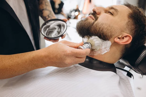 Närbild manliga händer med rakborste förbereda skägg av kunden för skärning i frisörsalongen. Skönhet, egenvård, stil, mode och manlig kosmetika koncept. — Stockfoto