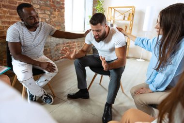 Çok ırklı gençler, kadın ve erkekler psikolojik destek grubunda yan yana oturuyorlar. Destek ve yardımcı konsept