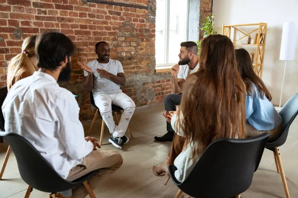 年轻的多种族人，男人和女人坐在一起的心理支持小组，室内。支助和助理概念 — 图库照片