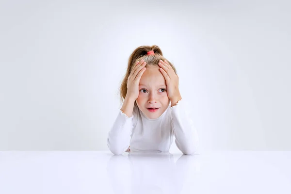 Porträtt av vackra skolflicka sitter och tittar på kameran isolerad på vit bakgrund. Lycklig barndom, utbildning — Stockfoto