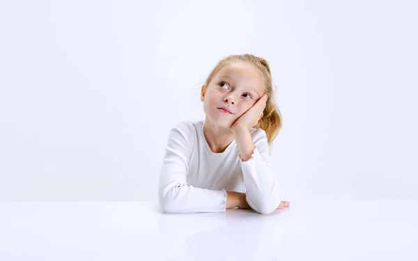 Porträtt av vackra skolflicka sitter och tittar på kameran isolerad på vit bakgrund. Lycklig barndom, utbildning — Stockfoto