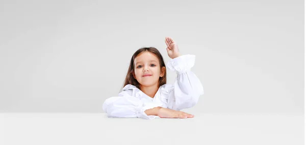 Portret van beuatiful schoolmeisje zitten en kijken naar camera geïsoleerd op witte achtergrond. — Stockfoto