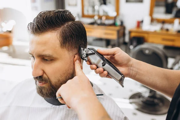 Un hombre que se corta el pelo en la peluquería. Peluquería profesional en el proceso de trabajo. Belleza, cuidado personal, estilo, moda, salud y cosméticos masculinos concepto. —  Fotos de Stock