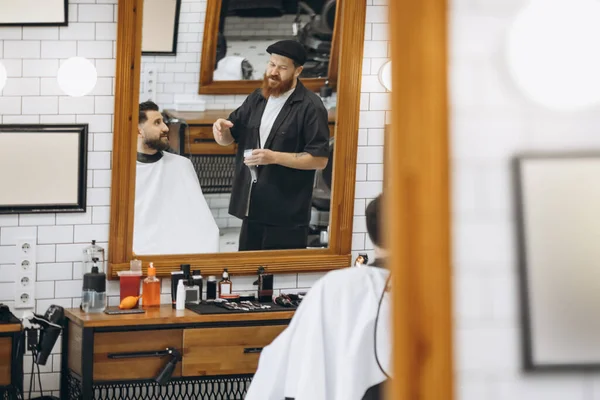 Two handsome men at barbershop. Stylish red-bearded barber and client during haircut process. Beauty, healthcare and male cosmetics concept. — Stock Photo, Image