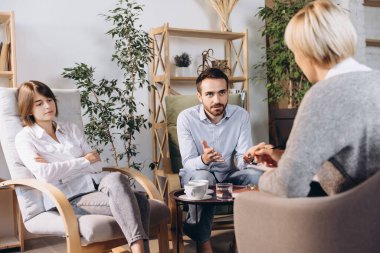 Psikolog randevusunda. Evli çift, üzgün, depresif erkek ve kadın aile sorununu çözmek için danışmanla buluşuyor.