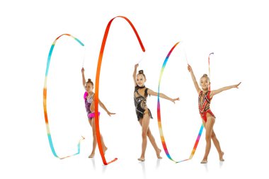 Üç kurdeleli bir etkinlik. Grup spor etkinliğindeki küçük güzel ritmik jimnastik sanatçılarının portresi beyaz stüdyo arka planında izole edilmiş..