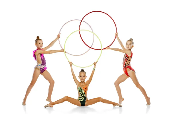 Retrato de pequeños y bellos artistas de gimnasia rítmica en un evento deportivo de grupo aislado sobre fondo blanco del estudio. Concepto de acción, equipo, espectáculo — Foto de Stock