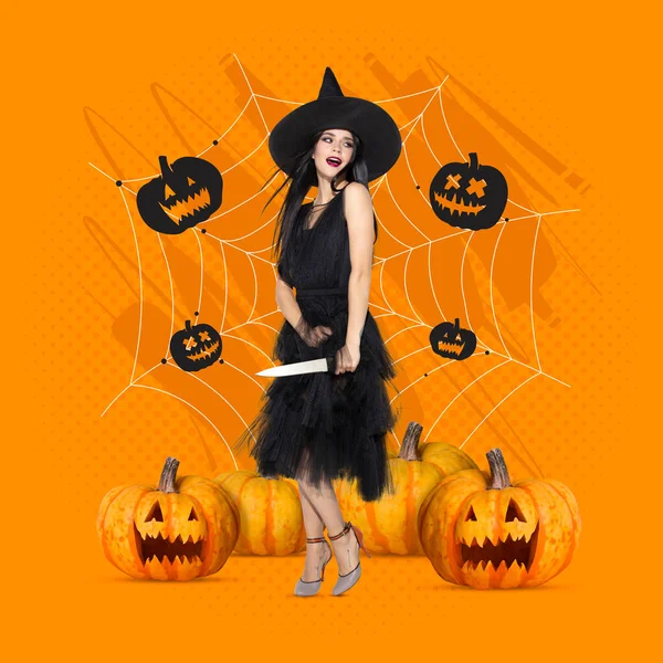 Młoda kobieta w czarnym kapeluszu w obrazie czarownicy stojącej wśród dyń Halloween na pomarańczowym tle koloru — Zdjęcie stockowe