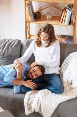 Mutlu evli çift evde, evde birlikte vakit geçiriyor. Kanepede oturan genç adam ve kadın. Aile kavramı, ilişki
