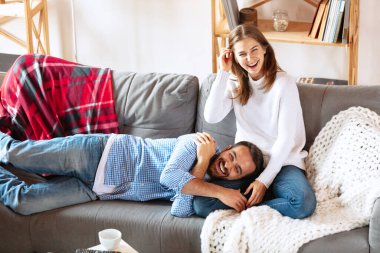 Mutlu evli çift evde, evde birlikte vakit geçiriyor. Kanepede oturan genç adam ve kadın. Aile kavramı, ilişki