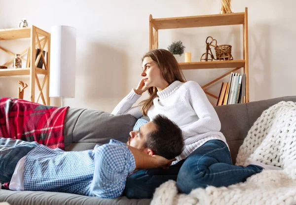 Glada gifta par som tillbringar tid hemma, inomhus. Ung man och kvinna sitter på soffan. Begreppet familj, förhållande — Stockfoto