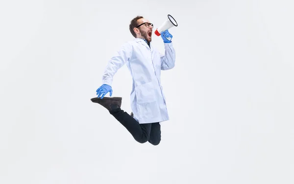 One excited man, chemist, doctor jumping and shouting at megaphone isolated on white background. — Stock Photo, Image