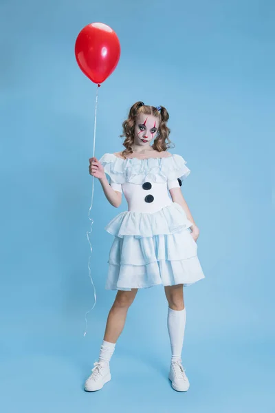 Conceptual image of charming young girl in Halloween costume of movie character with spooky facial expression isolated over blue background — Stock Photo, Image