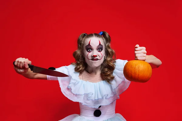 Tema espeluznante de Halloween. Chica rubia mística con vacaciones brillantes componen cuchillo aislado sobre fondo rojo — Foto de Stock