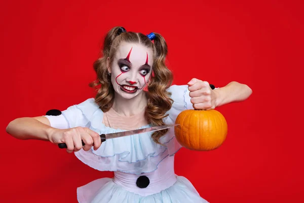 Tema espeluznante de Halloween. Chica rubia mística con vacaciones brillantes componen cuchillo aislado sobre fondo rojo — Foto de Stock