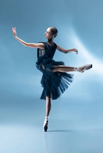 Młoda i pełna wdzięku tancerka baletowa w czarnym stroju sceny, sukienka odizolowana na białym niebieskim tle studio w neonowym świetle. — Zdjęcie stockowe