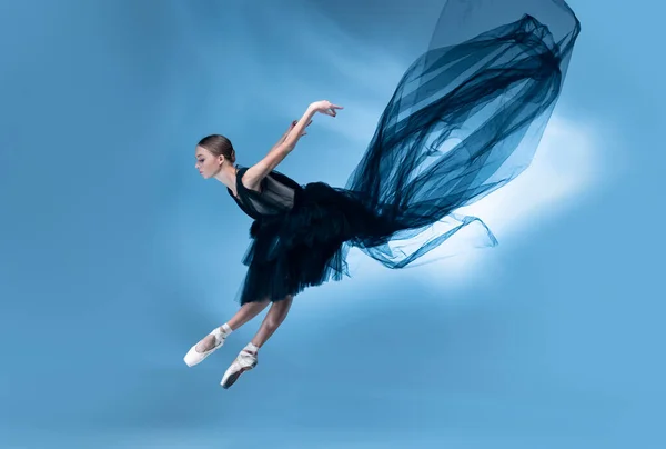 Giovane e graziosa ballerina di balletto in abito da palcoscenico nero, vestito isolato su sfondo bianco blu studio in luce al neon. — Foto Stock