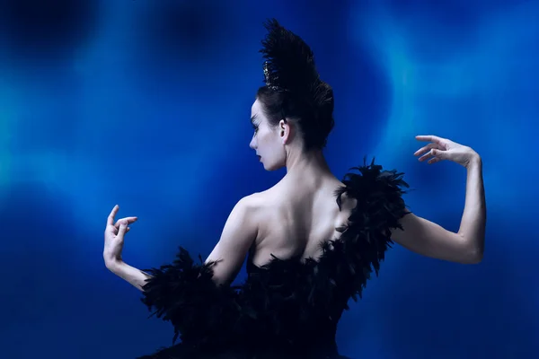 Widok z tyłu pięknej kobiety, elastyczna balerina w czarnym stroju baletowym, taniec tutu w niebieskim studio pełnym światła. — Zdjęcie stockowe