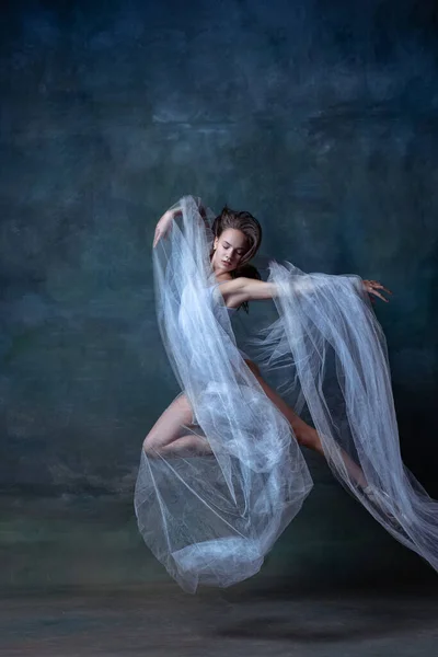 Студийный кадр молодой гибкой балерины, танцующей изолированно на темном винтажном фоне студии. Искусство, движение, концепция действия. — стоковое фото