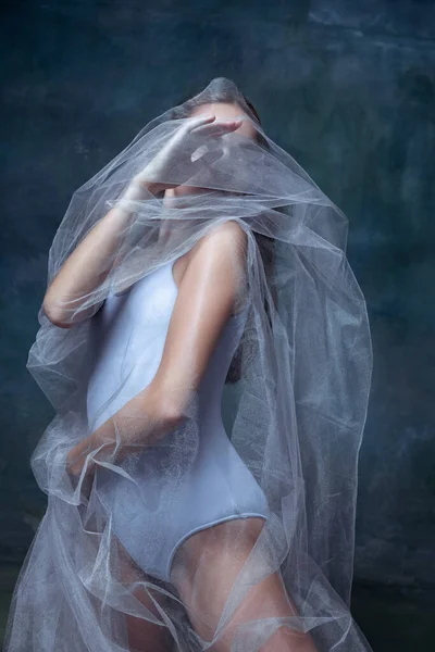 Портрет молодой красивой девушки, балерины позирует с белой прозрачной тканью изолированы на темном винтажном фоне студии. — стоковое фото