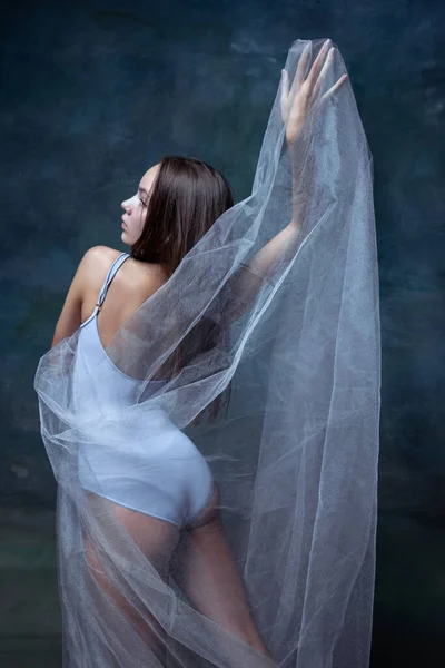 Close-up de menina bonita jovem, bailarina posando com pano transparente branco isolado no fundo do estúdio vintage escuro. — Fotografia de Stock