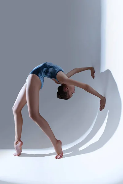 若く優雅なバレエダンサー、光のスタジオの背景に隔離されたバレリーナダンス。芸術、運動、行動、柔軟性、インスピレーションの概念. — ストック写真