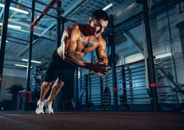 Kaslı bir sporcunun portresi, vücut geliştirme egzersizleri spor salonunda tek başına, kapalı alanda. Spor anlayışı, aktivite, sağlıklı yaşam tarzı