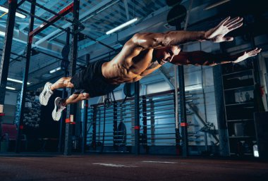 Kaslı bir sporcunun portresi, vücut geliştirme egzersizleri spor salonunda tek başına, kapalı alanda. Spor anlayışı, aktivite, sağlıklı yaşam tarzı