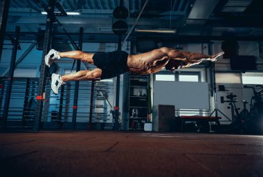 Kaslı bir sporcunun portresi, vücut geliştirme egzersizleri spor salonunda tek başına, kapalı alanda. Spor anlayışı, aktivite, sağlıklı yaşam tarzı