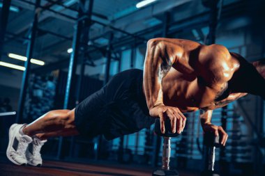 Kaslı bir sporcunun portresi, vücut geliştirme egzersizleri spor salonunda tek başına, kapalı alanda. Spor anlayışı, aktivite, sağlıklı yaşam tarzı