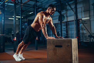 Kaslı bir sporcunun portresi, vücut geliştirme egzersizleri spor salonunda tek başına, kapalı alanda. Spor anlayışı, aktivite, sağlıklı yaşam tarzı