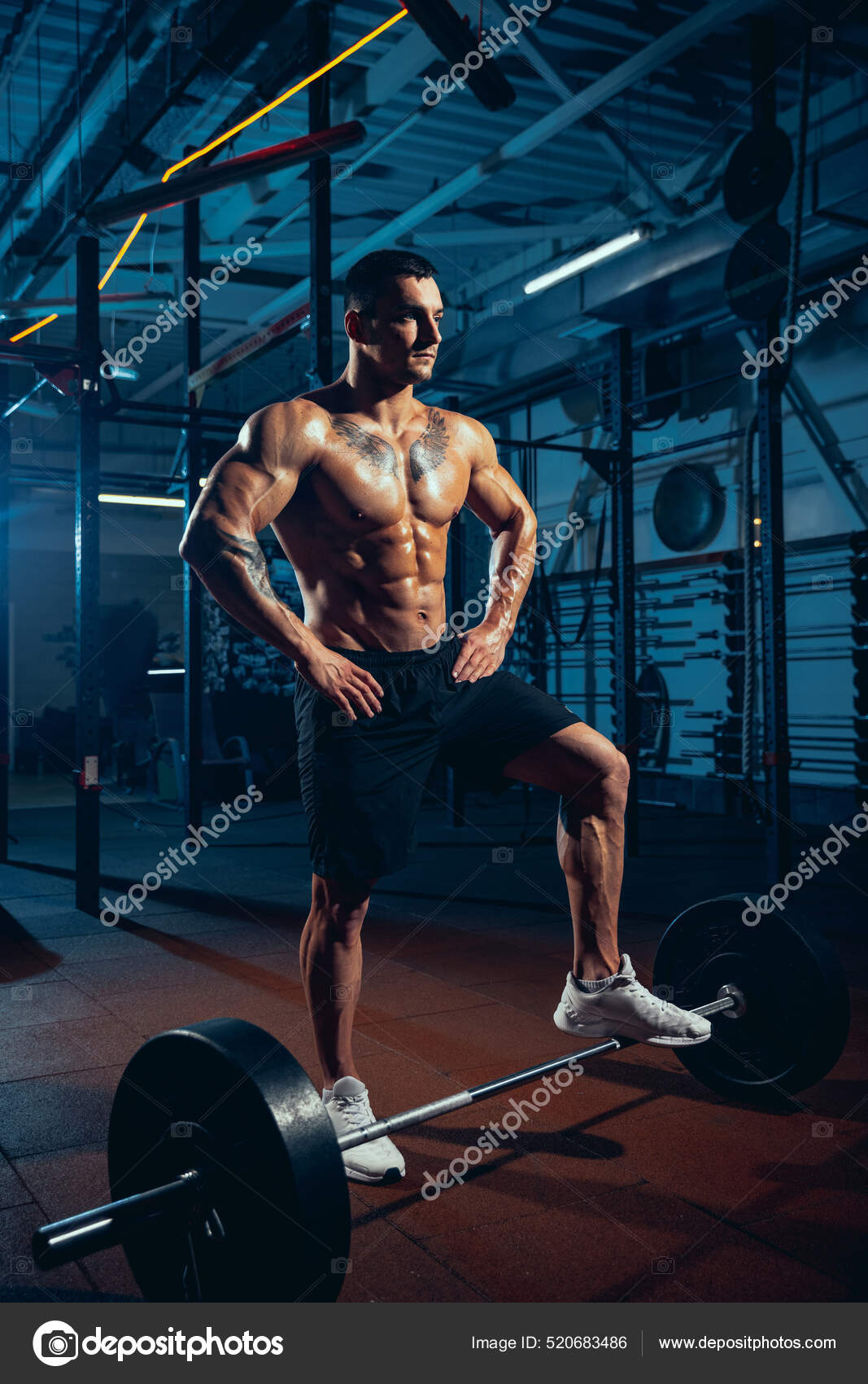 Young strong man muscled athlete bodybuilder training alone at