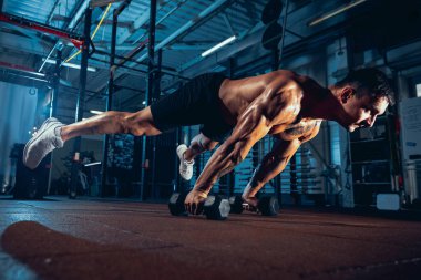 Kaslı bir sporcunun portresi, vücut geliştirme egzersizleri spor salonunda tek başına, kapalı alanda. Spor anlayışı, aktivite, sağlıklı yaşam tarzı