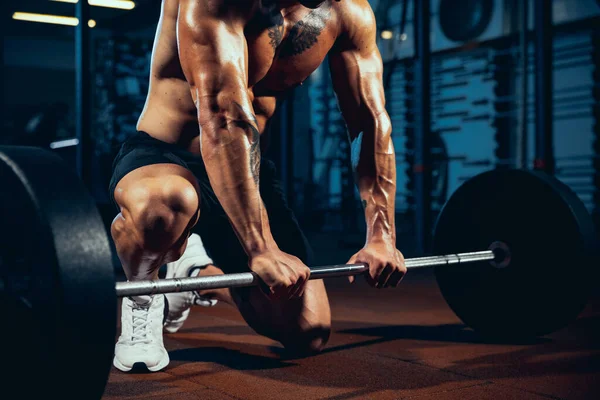 Jovem de close-up, atleta musculado, fisiculturista com barra pesada no ginásio esportivo, dentro de casa. Conceito de esporte, atividade, estilo de vida saudável — Fotografia de Stock