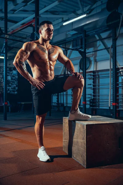 Retrato de hombre guapo, deportivo, culturista posando en el gimnasio deportivo, en interiores. Concepto de deporte, actividad, estilo de vida saludable —  Fotos de Stock