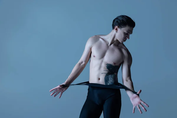 Hombre musculoso joven de cerca, bailarín de ballet masculino posando aislado en el fondo del viejo estudio de la marina. Arte, movimiento, concepto de inspiración. — Foto de Stock