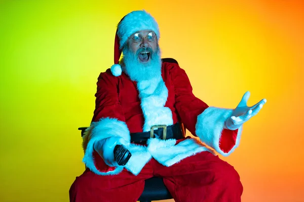 Porträt eines älteren Mannes, überrascht vom Weihnachtsmann, der im Kino sitzt und sich Filme ansieht, drinnen. Frohes Neues Jahr 2022, Weihnachtskonzept — Stockfoto