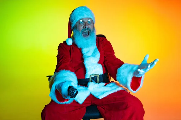 Retrato de homem sênior, surpreendeu Papai Noel sentado e assistindo filme no cinema, dentro de casa. Feliz Ano Novo 2022, conceito de Natal — Fotografia de Stock