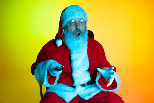 Ritratto di uomo anziano, sorpreso Babbo Natale seduto a guardare film al cinema, al chiuso. Felice anno nuovo 2022, concetto di Natale — Foto Stock