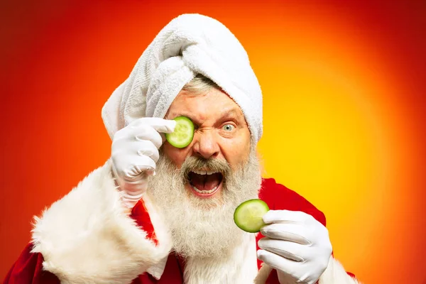 Emotional senior man, Santa Claus at spa salon before holidays isolated on red yellow background in neon. New Year 2022 — Stock Photo, Image