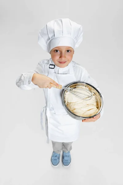 Портрет маленького счастливого мальчика в белом поваре, куртке шеф-повара и шляпе, стоящих изолированно на белом фоне студии. — стоковое фото