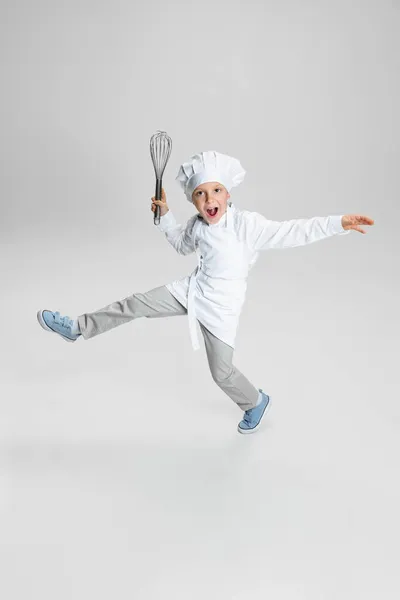 Retrato de niño feliz en cocinero blanco, chaqueta de chef y sombrero saltando aislado sobre fondo blanco estudio. — Foto de Stock