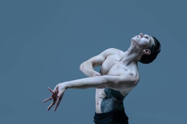 Genç bir adamın yarım boy portresi. Esnek erkek dansçı. Eski donanma stüdyosunun arka planında yalnız dans ediyor. Sanat, hareket, ilham kavramı.