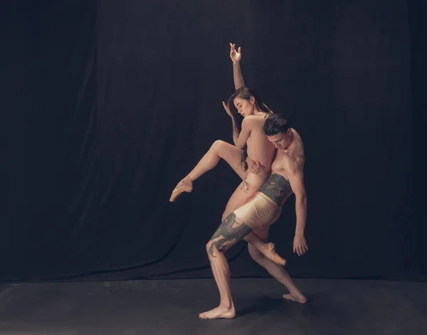 Dva flexibilní tanečníci, mladý muž a žena v moderním uměleckém provedení izolovaní na černém pozadí studia. Umění, pohyb, inspirace. — Stock fotografie