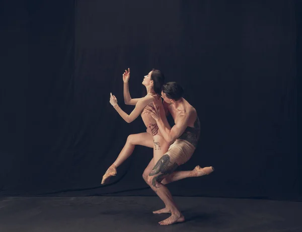 Два гибких танцора, молодой человек и женщина в современном художественном перформансе изолированы на фоне черной студии. Искусство, движение, вдохновение. — стоковое фото