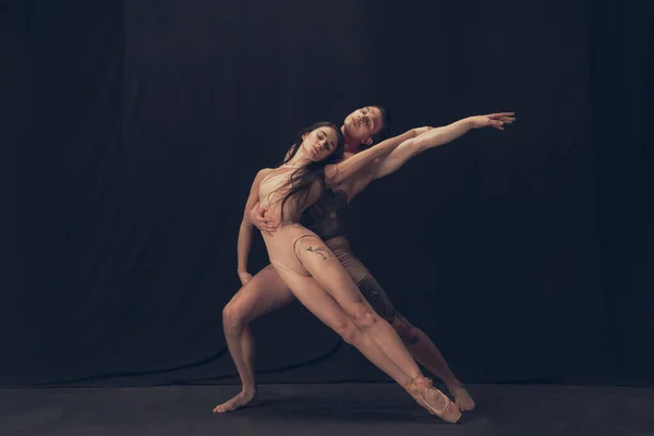 Dois dançarino flexível, jovem e mulher em performance de arte moderna isolado no fundo do estúdio preto. Arte, movimento, conceito de inspiração. — Fotografia de Stock