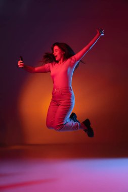 Karanlık stüdyo arka planında neon ışıkta izole edilmiş güzel, gülümseyen bir kızın portresi. İnsan duyguları kavramı, yüz ifadesi