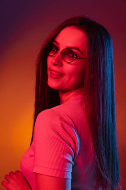 Karanlık stüdyo arka planında neon ışıkta izole edilmiş sevimli mutlu kız. İnsan duyguları kavramı, yüz ifadesi