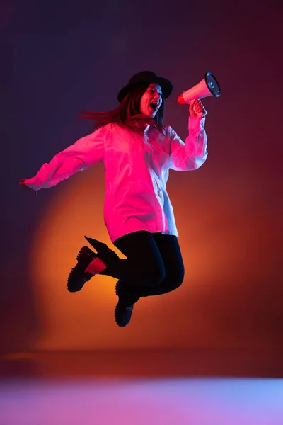 Emotioneel jong meisje schreeuwen naar megafoon geïsoleerd op donkere studio achtergrond in neon licht. — Stockfoto