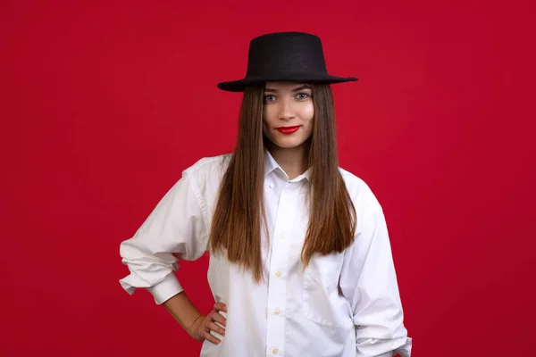 Κομψή νεαρή όμορφη κοπέλα φορώντας μαύρο καπέλο απομονώνονται σε σκοτεινό φόντο στούντιο σε νέον φως. Έννοια των συναισθημάτων, μόδα — Φωτογραφία Αρχείου